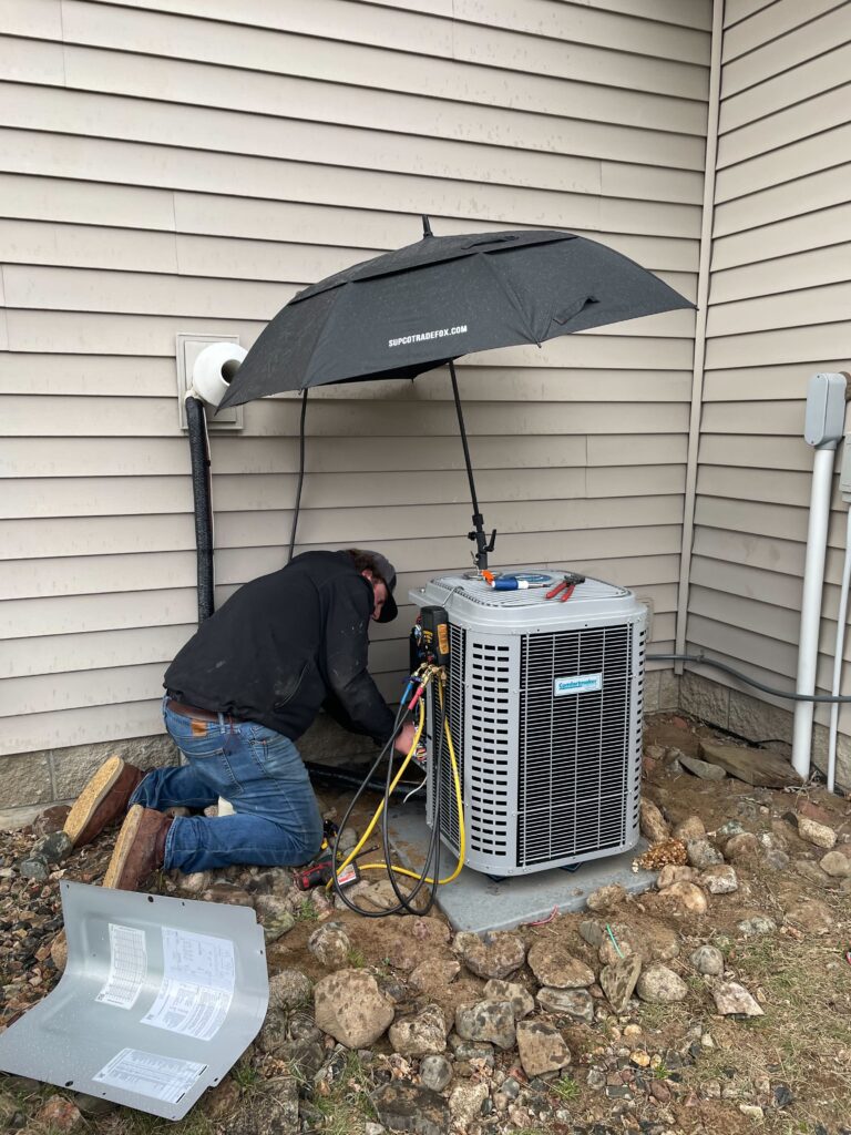 A man works on an outdoor A/C unit