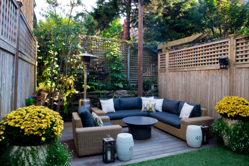 A small backyard living area with a tall fence and outdoor furniture.