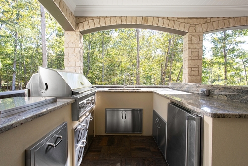 A covered outdoor kitchen with a built-in grill, sink, and dishwasher.