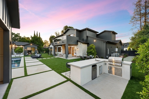 A modern-style backyard with an outdoor kitchen and a pool.