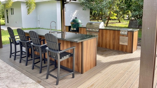 An outdoor kitchen with a seating bar, built-in grill, and sink.