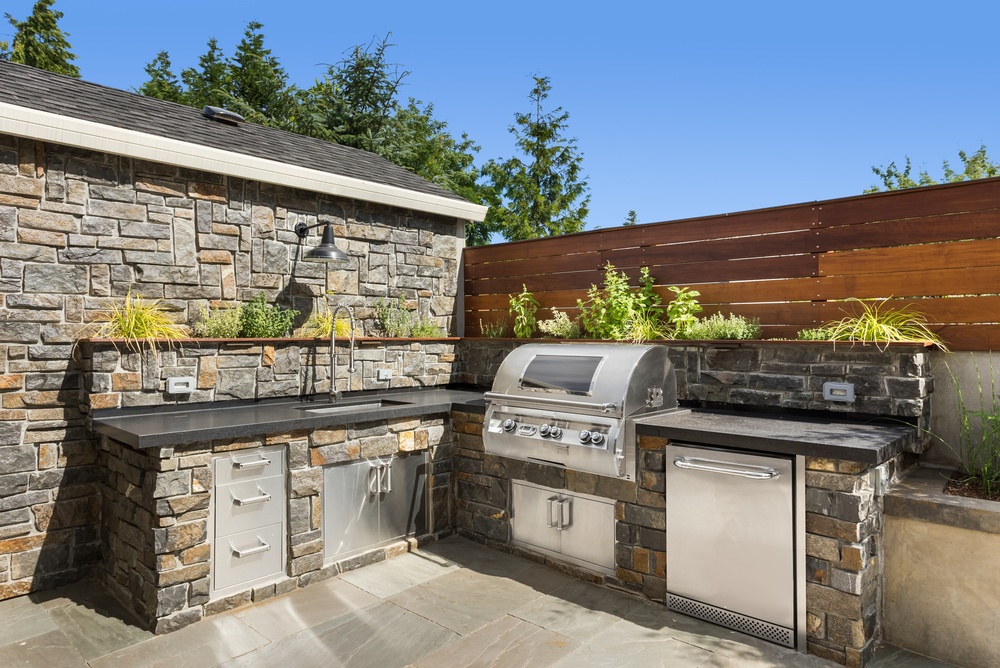 An outdoor kitchen featuring a sink, washing machine, and grill.